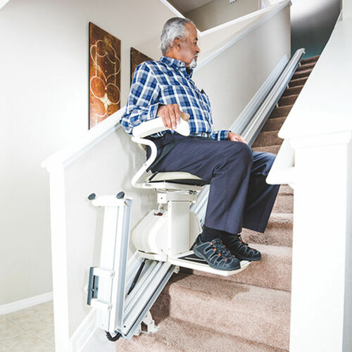 Man using a stairlift on a set of stairs in a home setting.