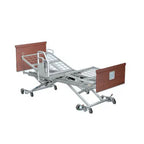 An adjustable electric hospital bed with a silver metal frame, mesh mattress, and reddish-brown head and footboards on casters, shown against a plain white background.